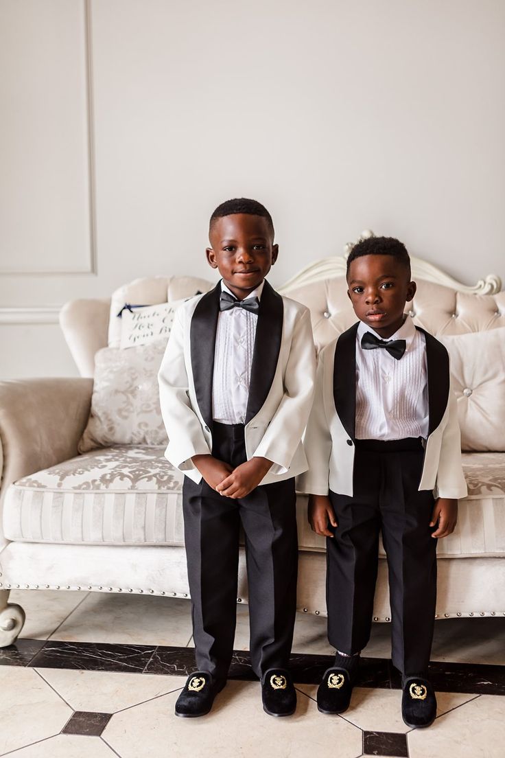 Two young ring bearers in white tuxedo jackets and bow ties