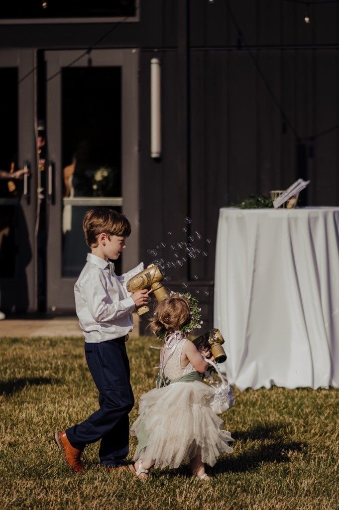 A boy and flower girl playing with bubble guns at a wedding reception