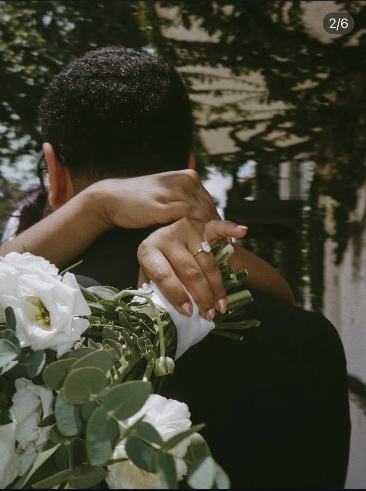 A bride embracing her groom while holding a white bouquet